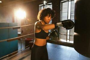 mulheres auto defesa menina poder. africano americano mulher lutador Treinamento socos em boxe anel. saudável Forte menina soco boxe bolsa. Treinamento dia dentro boxe academia. força em forma corpo exercite-se treinamento. foto