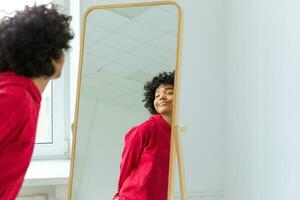amor você mesmo. lindo jovem sorridente africano americano mulher dançando desfrutando dela espelho reflexão. Preto senhora olhando às espelho olhando confiante e feliz. auto amor conceito. foto