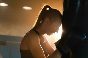 mulheres auto defesa menina poder. Forte mulher lutador em repouso depois de luta Treinamento em boxe anel. Forte menina cansado depois de soco boxe bolsa. Treinamento dia dentro academia. força em forma corpo exercite-se treinamento. foto