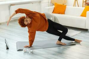 ginástica exercite-se treinamento. jovem saudável africano menina praticando ioga às lar. mulher dentro roupa de esporte Treinamento pilates fazendo Esportes exercício em ioga esteira em chão interior. menina ter Treinamento dar certo. foto