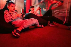 dois Rapazes gamers jogar controle vídeo jogos console dentro vermelho jogos sala. foto