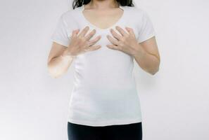 jovem mulher vestindo camiseta segurando mãos em seio pequeno foto