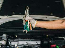 mão do carro mecânico com chave inglesa auto mecânico reparar manutenção e carro inspeção foto