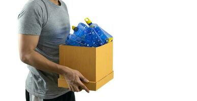 uma homem carregando uma caixa com uma plástico garrafa para estar reciclado foto
