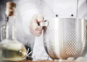 cozinha chefe de cozinha com escorredor de macarrão foto