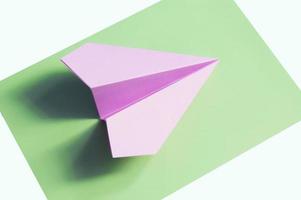 um jato de origami rosa sobre fundo verde foto