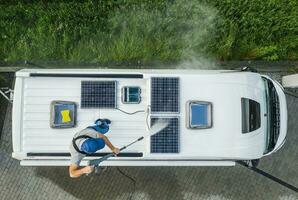 homens pressão lavando rv campista furgão cobertura equipado com solar painéis foto