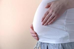 close-up autêntico de uma jovem grávida de pijama acariciando sua barriga