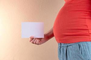 uma visão aproximada da barriga de uma mulher grávida vestida de vermelho foto