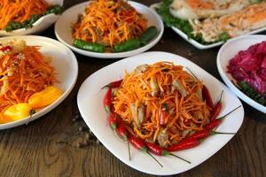 Salada de cenoura de vegetais coreana em uma mesa de carvalho com pimentas frescas foto