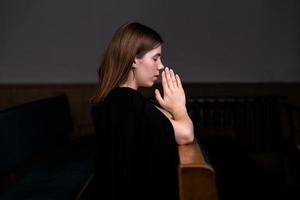 uma menina cristã de camisa branca está orando com o coração humilde na igreja foto