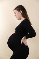 vista lateral de uma atraente mulher grávida acariciando sua barriga