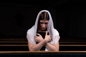 uma menina cristã orando com o coração humilde na igreja foto