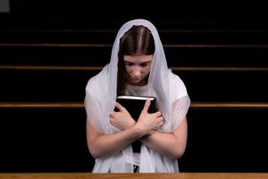 uma menina cristã orando com o coração humilde na igreja foto