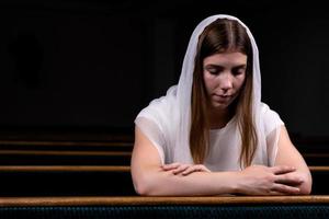 uma menina cristã orando com o coração humilde na igreja foto