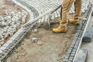 trabalhador pavimentação residencial caminho usando granito tijolos foto