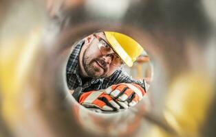 trabalhador olhando dentro metal hvac tubo foto