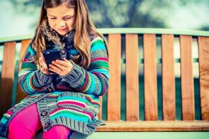 menina em Banco com Smartphone foto