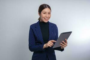 mulher asiática sorrindo e segurando o tablet digital em pé sobre fundo branco foto