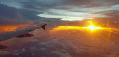 silhueta do aeronave ou avião asa em Sombrio céu com pôr do sol luz flare fundo. transporte, viagem e beleza do natureza conceito foto