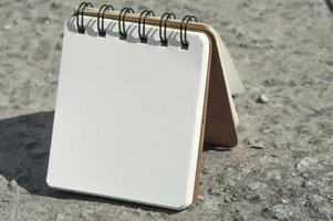 caderno com papel branco no chão foto