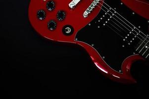 closeup de guitarra elétrica vermelha em fundo preto foto