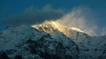 luz solar cai em a gelado cume por aí a coberto de nuvens pico do Annapurna sul dentro a Nepal himalaya. foto