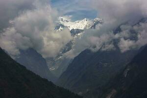 uma lindo panorama do nuvens cobertura a flancos do a sul Annapurna alcance visto a partir de a Vila do chomong em a Annapurna base acampamento trilha dentro a Nepal himalaya. foto