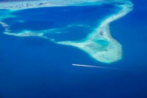 ilhas tropicais e atóis nas maldivas de vista aérea. famoso destino de viagem e férias de luxo ou conceito de férias de verão. paisagem aérea do mar azul e resorts, hotéis. natureza bela foto