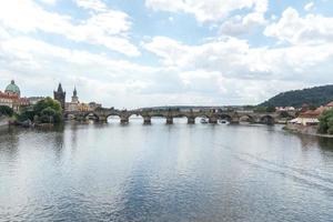 vista panorâmica da ponte de charles ponte em arco de pedra medieval que cruza o rio vltava moldau na república tcheca de praga foto