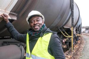 mecânico afro-americano usando capacete de equipamento de segurança e jaqueta, verificando e inspecionando o trem de engrenagens foto