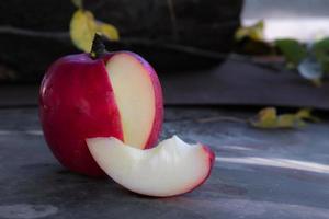 close-up de uma maçã vermelha fatiada em uma mesa de madeira foto