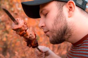 homem está comendo shish kebab foto