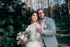 foto de casamento da noiva e do noivo em uma cor cinza-rosa na natureza na floresta e nas rochas