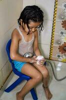 fofa indiano menina tendo banho durante a verão período de férias temporada, fofa ásia criança lavando dentro uma banheiro, criança tomando banho estilo de vida conceito foto