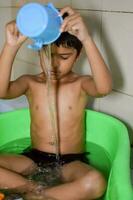 fofa indiano Garoto tendo banho durante a verão período de férias temporada, fofa ásia criança lavando dentro uma banheiro, criança tomando banho estilo de vida conceito foto