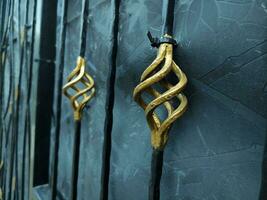 fechar-se do a ferro cerca com dourado enfeite em uma Preto fundo. velho metal portão com uma forjado padronizar. metal cerca com forjado elementos. foto