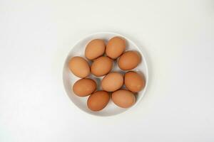 topo Visão do cru Castanho ovos em de madeira prato isolado em branco fundo. foto