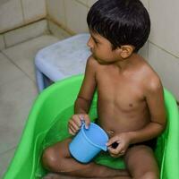 fofa indiano Garoto tendo banho durante a verão período de férias temporada, fofa ásia criança lavando dentro uma banheiro, criança tomando banho estilo de vida conceito foto