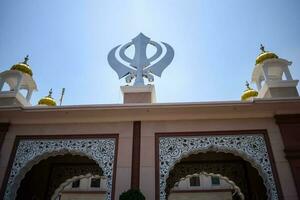 Khanda sikh piedosos religioso símbolo às Gurudwara Entrada com brilhante azul céu imagem é ocupado às irmã ganj sahib Gurudwara dentro Chandni chowk, oposto vermelho forte dentro velho Délhi Índia foto