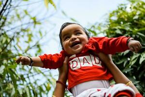 fofa pequeno indiano infantil sentado desfrutando ao ar livre tiro às sociedade parque dentro Délhi, fofa bebê Garoto sentado em colorida esteira com Relva em volta, bebê Garoto ao ar livre tiro foto