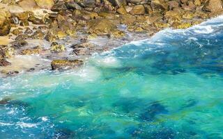 surfista ondas turquesa azul água pedras falésias pedregulhos porto escondido. foto