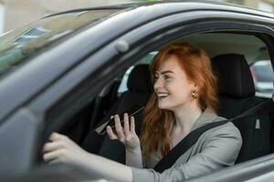 fechar-se do mulher usando Móvel telefone e falando em a alto falante enquanto dirigindo carro. mulher falando em no carro viva voz enquanto dirigindo foto