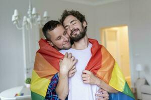 afetuoso masculino gay casal dentro de casa. homem abraçando dele namorado a partir de atrás às lar. gay casal a comemorar orgulho mês foto