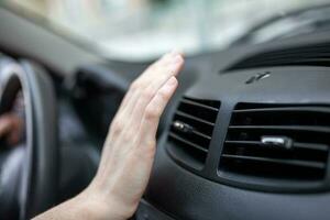 mulher ajustando a resfriamento dentro dela carro, fechar-se do mão motorista verificação ajustando ar a partir de condicionamento a resfriamento sistema com fluxo do frio ar dentro carro. foto