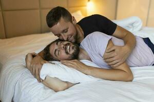 gay casal abraçando cada de outros com seus olhos fechado. dois jovem masculino amantes tocante seus rostos juntos enquanto deitado dentro cama dentro a manhã. afetuoso jovem gay casal vínculo às lar. foto