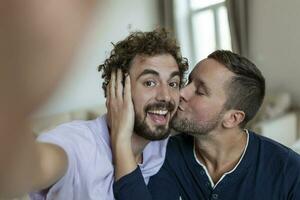 bonito gay homem sentado juntos às casa levando selfie com Móvel telefone. gay homem com dele parceiro sentado de levando uma auto retrato usando inteligente telefone. foto