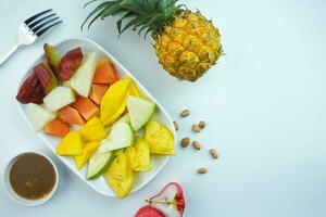 fatiado fruta salada, dentro Indonésia conhecido Como rujak buah ou lutis ou lotis. servido com picante Castanho açúcar molho e terra amendoim dentro uma prato em branco fundo foto