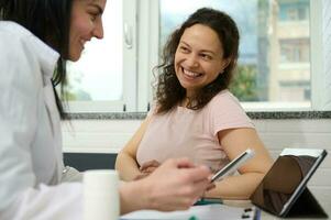 médico ginecologista discute com grávida mulher uma bebê ultrassom Varredura, examina gravídico paciente, receitar medicação foto