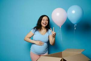 autêntico espantado expectante mãe segurando mão em dela grávida barriga, mostrando dois dedos, esperando gêmeos. bebê chuveiro foto